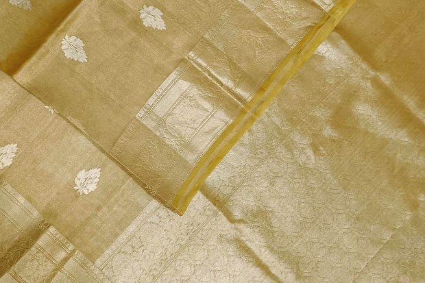 Yellow silk tissue handloom Banarasi saree with floral motifs in gold.