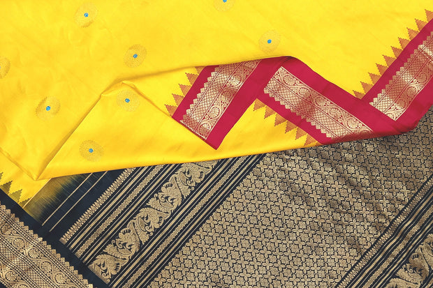 Handwoven Gadwal pure silk saree in yellow  with small motifs and contrast pallu in black .