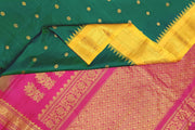 Handwoven Gadwal pure silk saree in bottle green  with small motifs   and  a contrast pallu in pink .