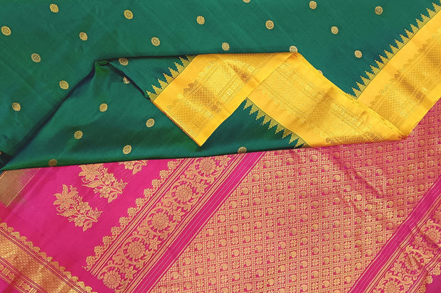 Handwoven Gadwal pure silk saree in bottle green  with small motifs   and  a contrast pallu in pink .