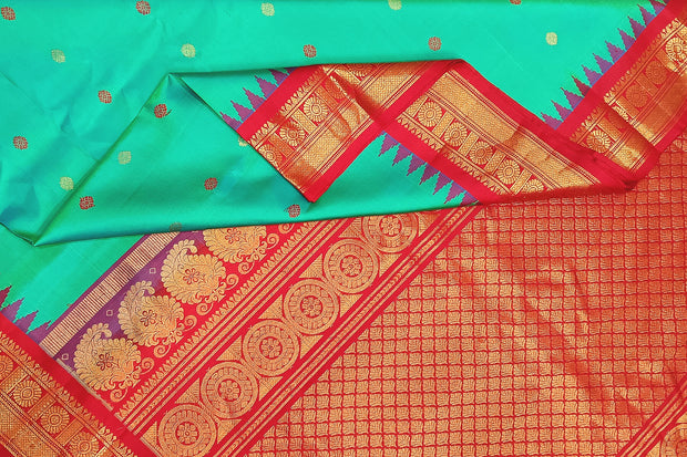 Handwoven Gadwal pure silk saree in  rama  green with  colourful  motifs on the body .
