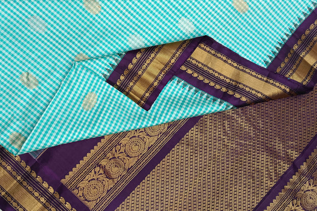 Handwoven Gadwal pure silk saree in fine checks in sky blue  & white  with gold & silver motifs all over the body.