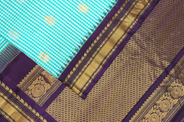 Handwoven Gadwal pure silk saree in fine checks in sky blue  & white  with gold & silver motifs all over the body.