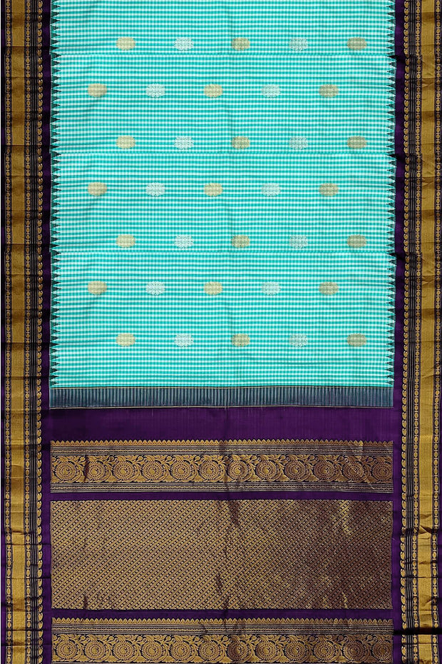 Handwoven Gadwal pure silk saree in fine checks in sky blue  & white  with gold & silver motifs all over the body.
