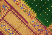 Handwoven Gadwal pure silk saree in bottle green with gold & silver motifs  all over the body.