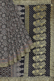 Modal silk saree in black  in hand block ajrakh print with zari border.