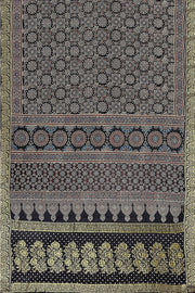Modal silk saree in black  in hand block ajrakh print with zari border.