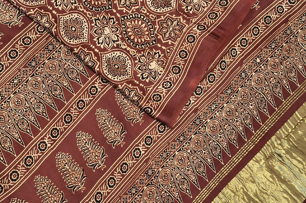 Modal silk saree in maroon with round motifs  in hand block ajrakh print and a tissue pallu